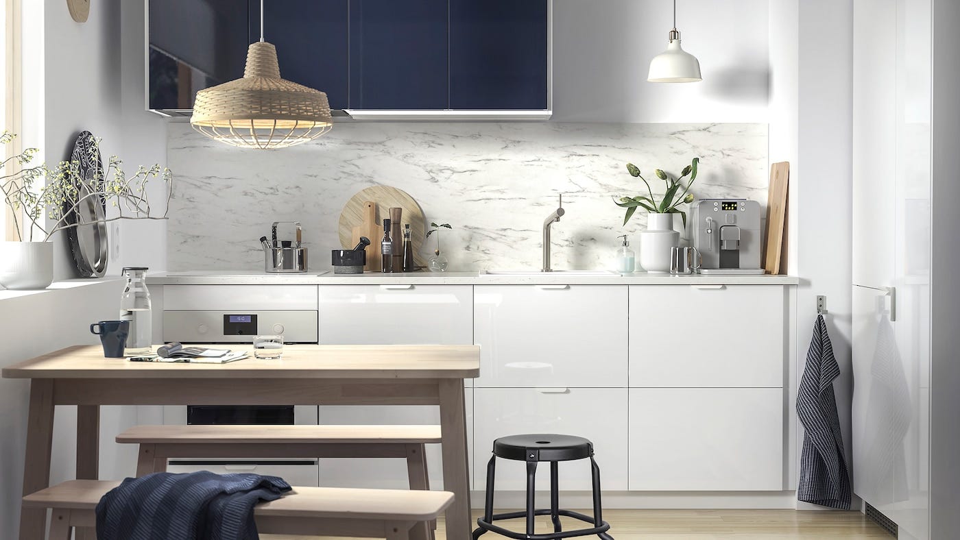 cocina blanca con comedor y armarios en azul