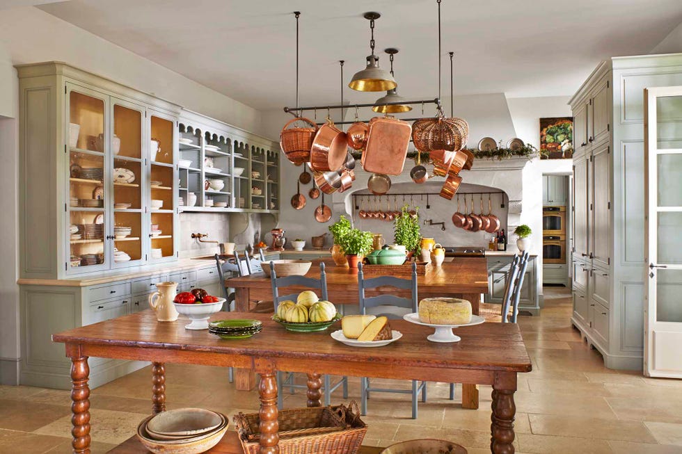 white kitchen in provence with copper pots and two farm tables
