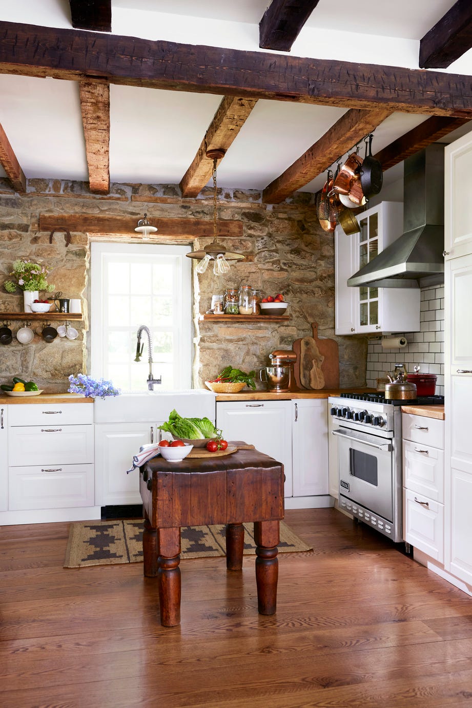 white farmhouse kitchen with a ceiling beams and a stone wall