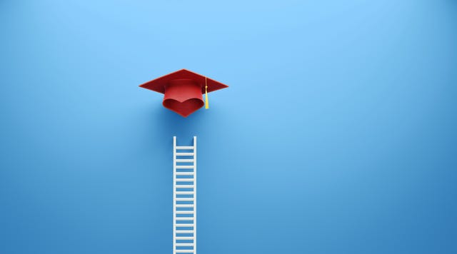 white ladder and red graduation cap leaning on blue wall