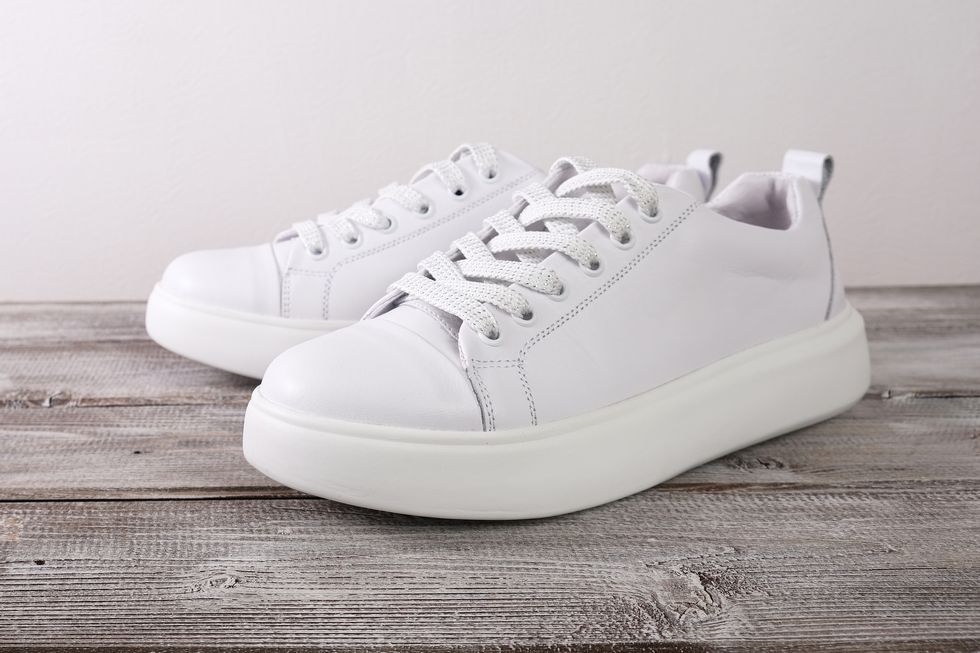 white leather casual sneakers on wooden background