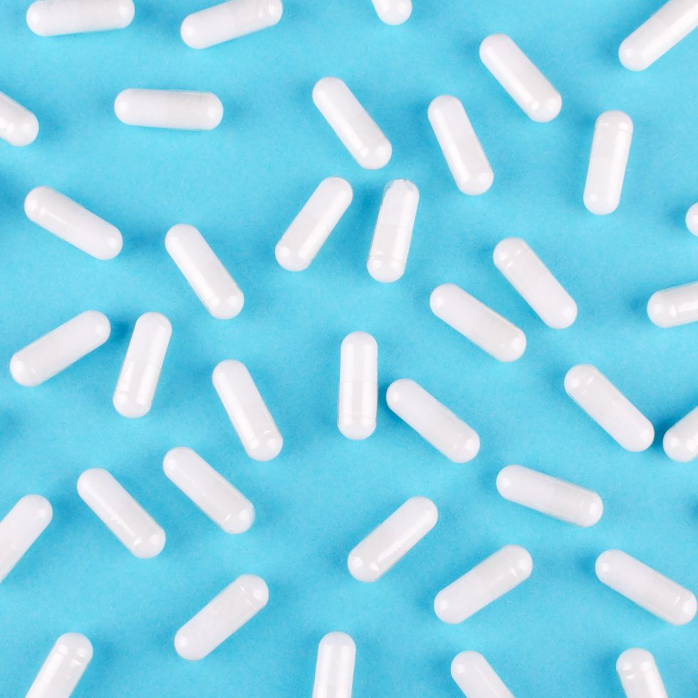 white medicine capsules on blue background, view from above