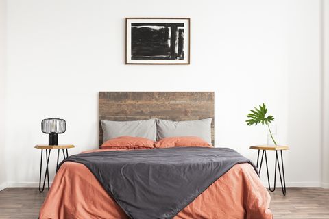white minimal bedroom with wooden headboard and coral and grey bedsheets