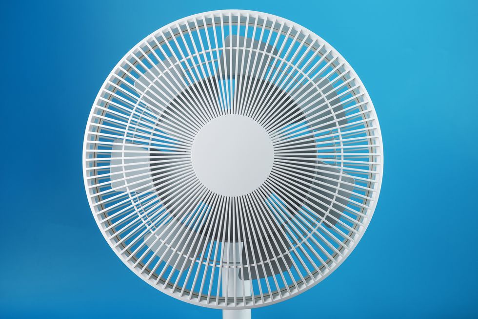 white modern electric fan for cooling the room on a blue background,romania