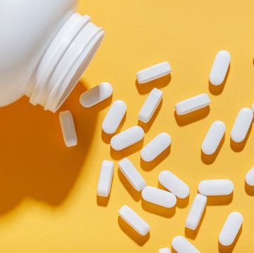 white pills are poured from a jar on a yellow background food supplement, multivitamins, medications