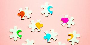 white puzzle pieces with a painted heart on a pink background polyamory concept