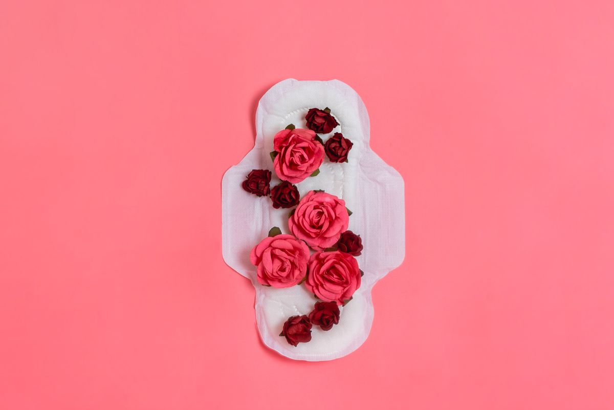 White sanitary pad with red and pink flowers on it, woman health or body positive concept. Pink background.  Flatlay. Copyspace