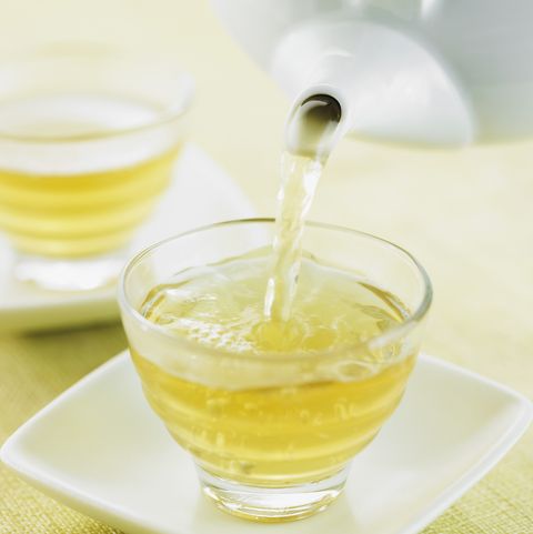 white teapot pouring white tea into a clear glass