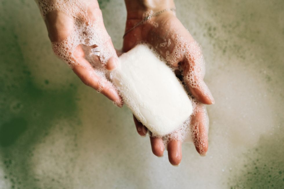 white toilet soap in female hands against the background of a fragrant foam bath natural beauty, daily skincare routine moisturizing, cleansing