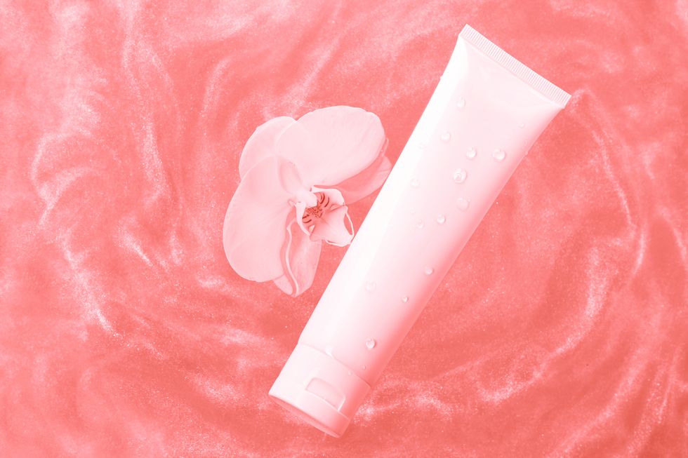 white tube face cream or hand cream and white orchid flower in pastel pink color liquid texture