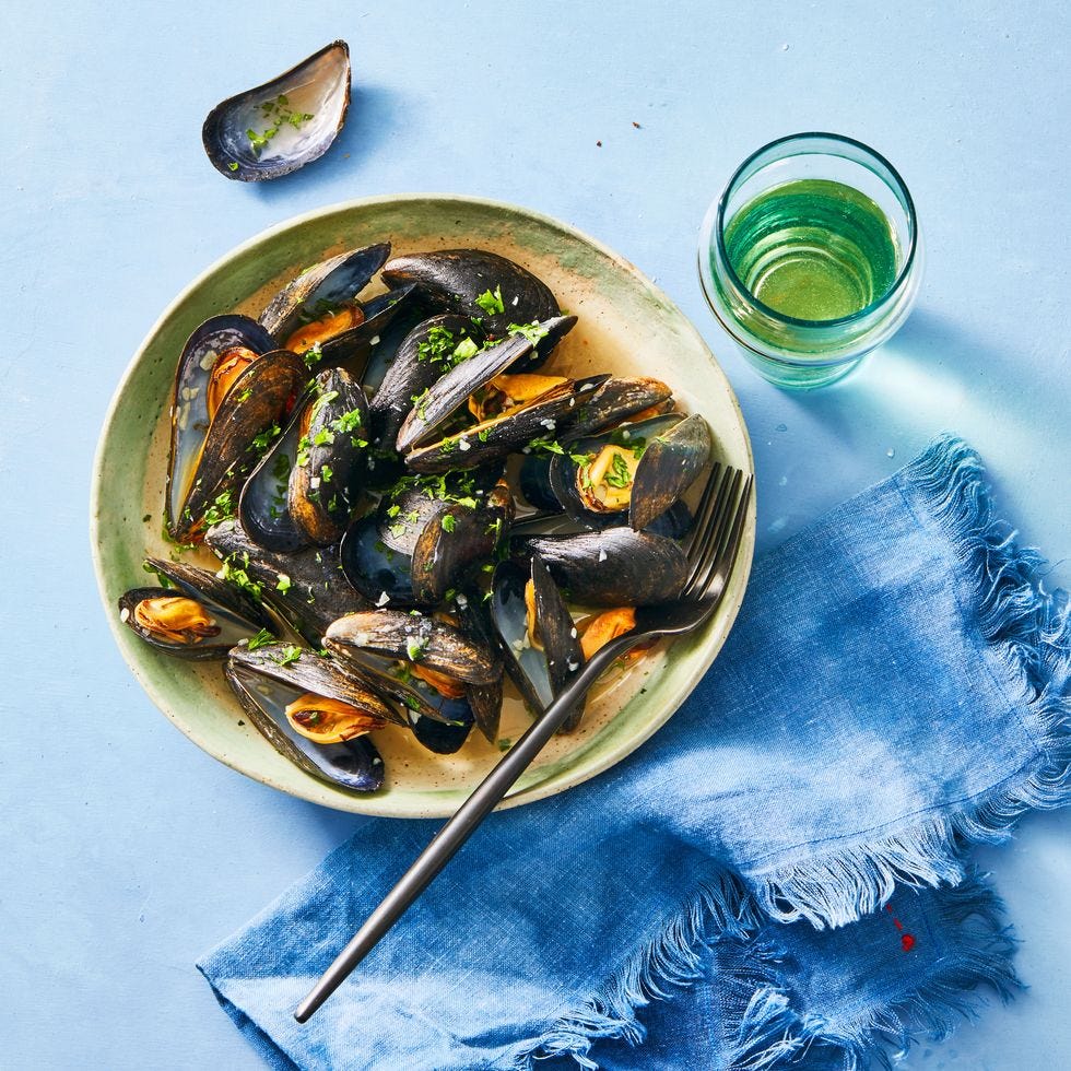 white wine mussels topped with fresh green herbs on a plate