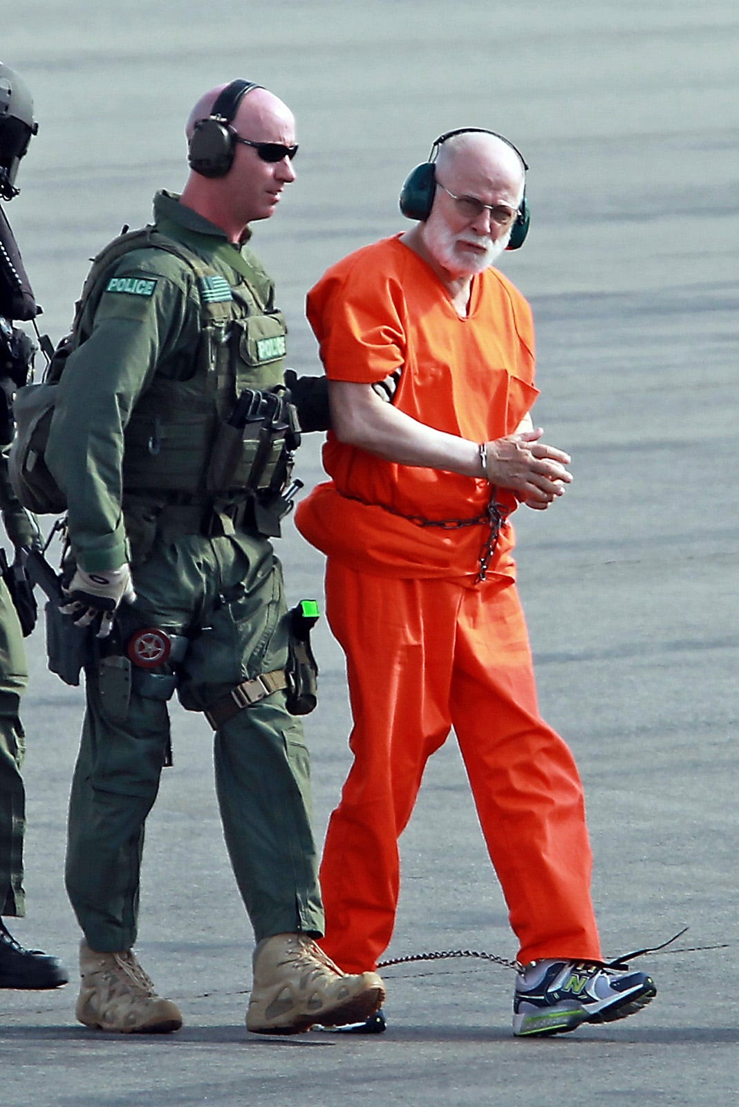 james bulger wearing an orange jumpsuit and being led in handcuffs to prison