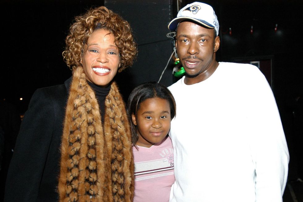 whitney houston, bobbi kristina brown, and bobby brown stand together and smile for a photo,