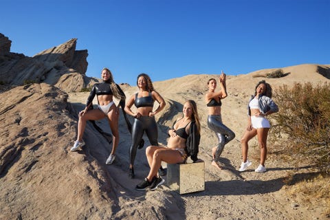 Group of women posing in athleticwear on rocky terrain under a blue sky