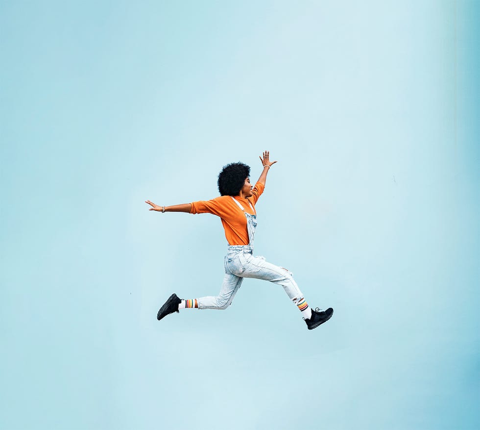 Stock photo of stylish afro woman jumping in front of white background