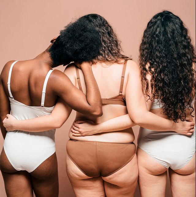 three femmes with their backs facing the camera embracing each other with arms wrapped around each other