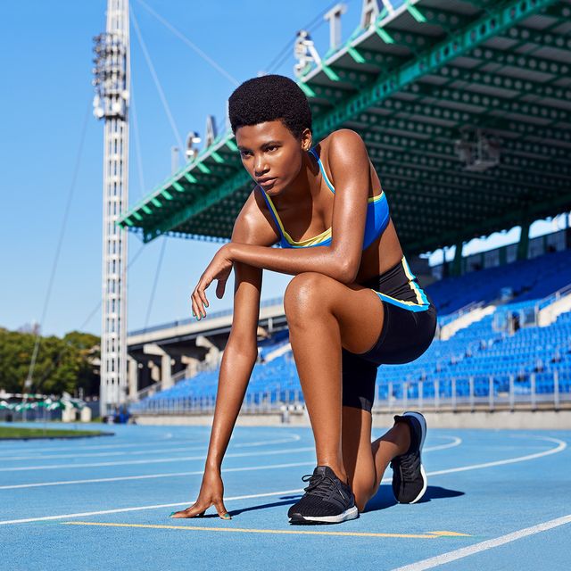 young female athlete crouching to start running on track