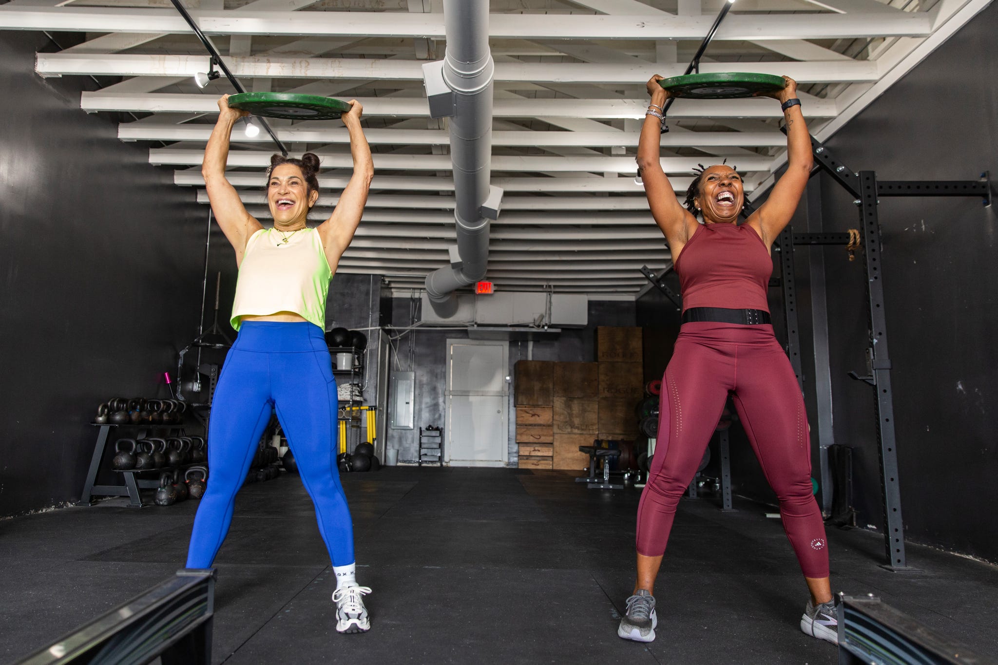 becky hennesy, left, and cynthia sanders lift weighed plates over their heads during a workout at dtx performance co in dallas, texas, on june 6, 2025.