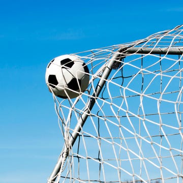 soccer ball moves through the air and hits the goal it's placed perfectly in the upper corner blue sky as background