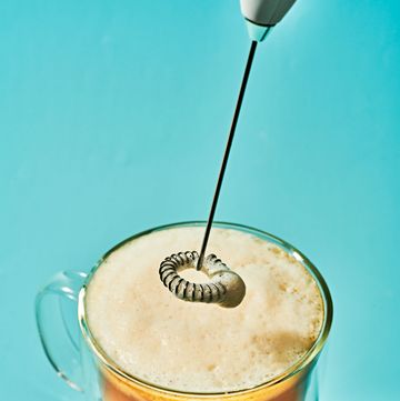 coffee in a clear mug, with a frother hovering above