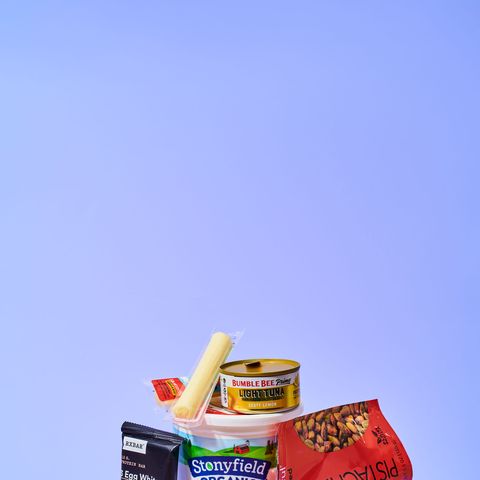 multiple snacks, such as string cheese and pistachios, on a blueish purple background