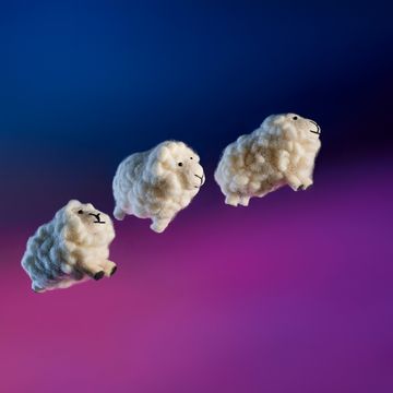 three wool sheep toys jumping through the air with a night sky background
