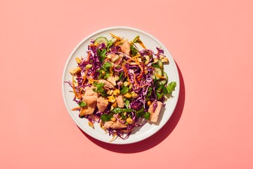 colorful salad with cabbage chicken and nuts on a pink background