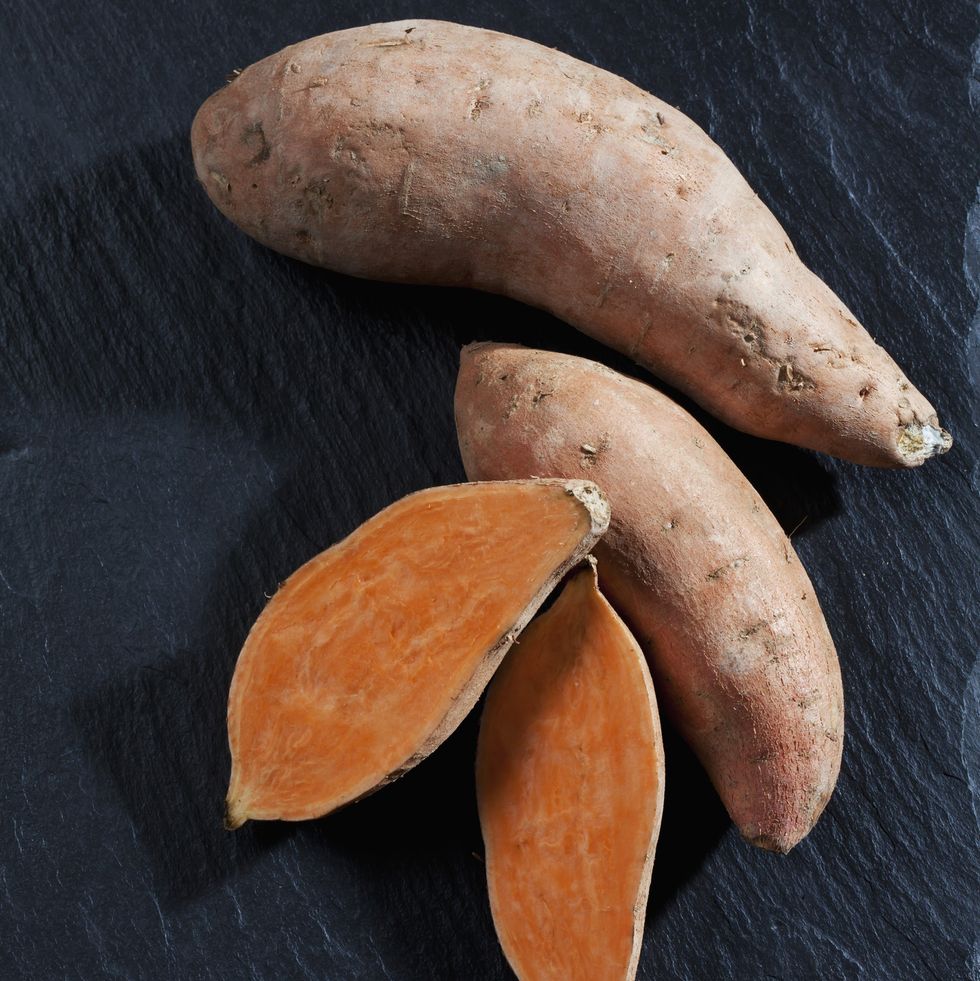whole and sliced sweet potatoes on slate