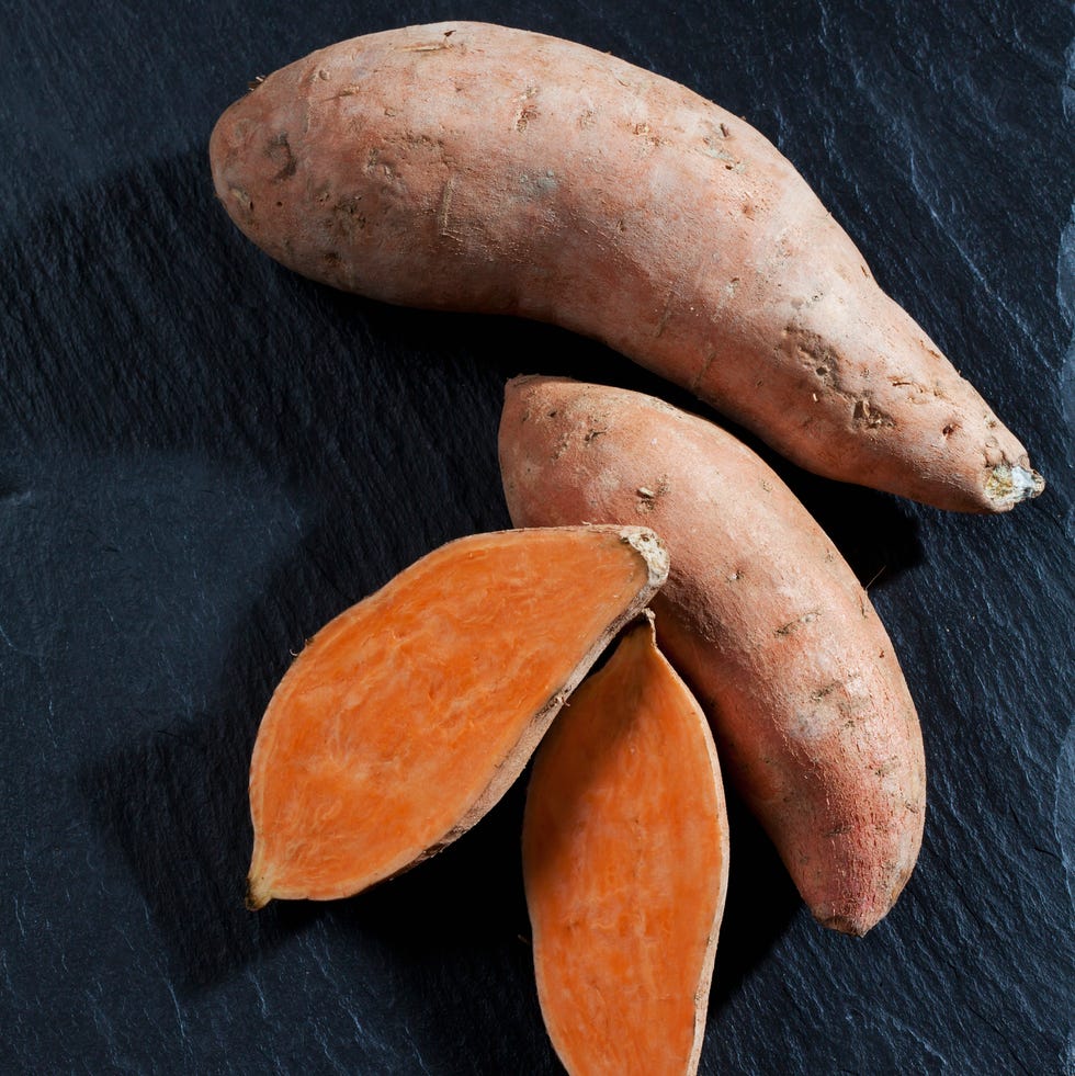 whole and sliced sweet potatoes on slate