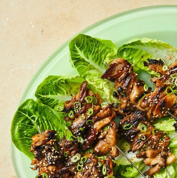 oyster skewers lined up on bed of lettuce, arranged on green plate
