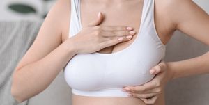 woman at home wearing white bra checking her breasts