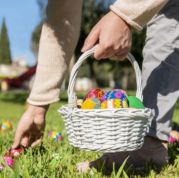close up of female holding an easter egg basket and hiding eggs in the grass on an out of focus background selective focus easter concept