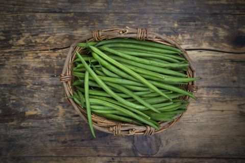 Wickerbasket of green beans on dark wood