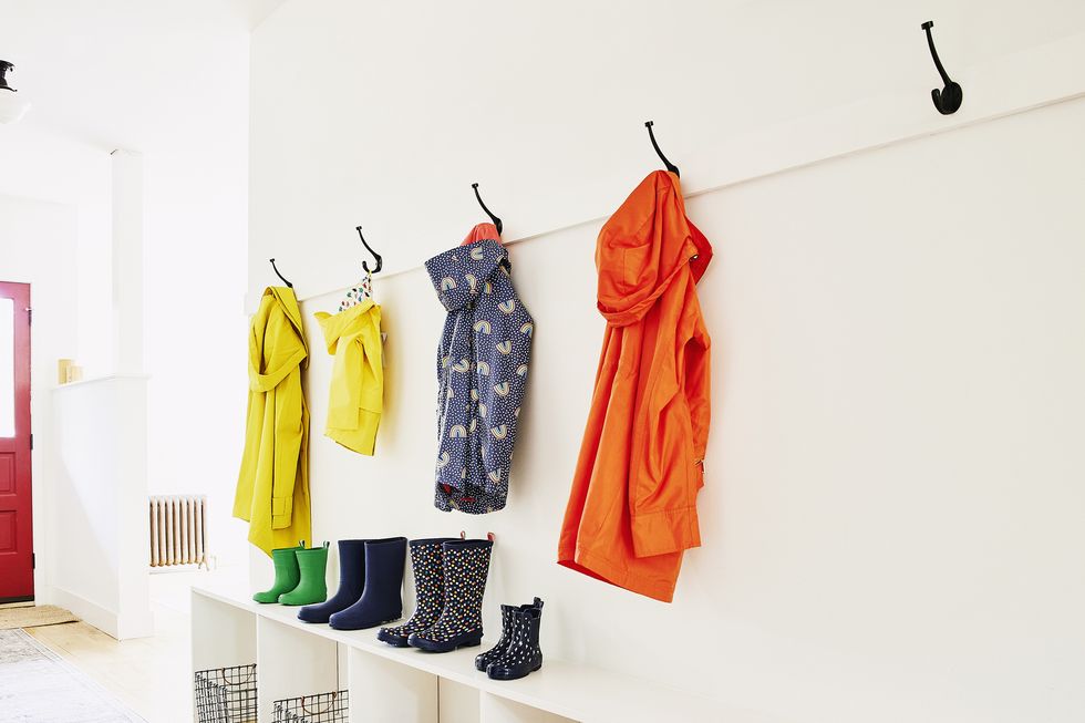 wide shot of different sizes of rainboots and raincoats in entryway of home