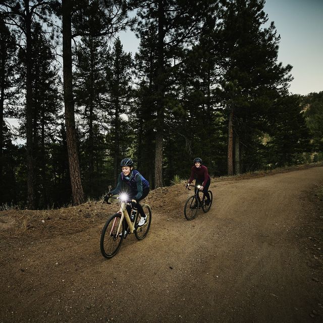 wide shot of female athletes on night gravel bike ride on forest road