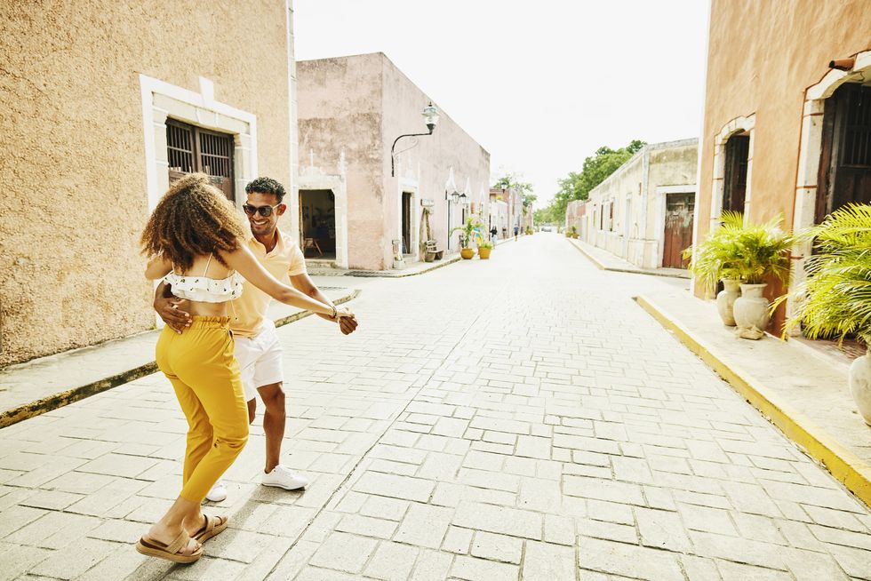 wide shot of smiling couple dancing in street while exploring town during vacation