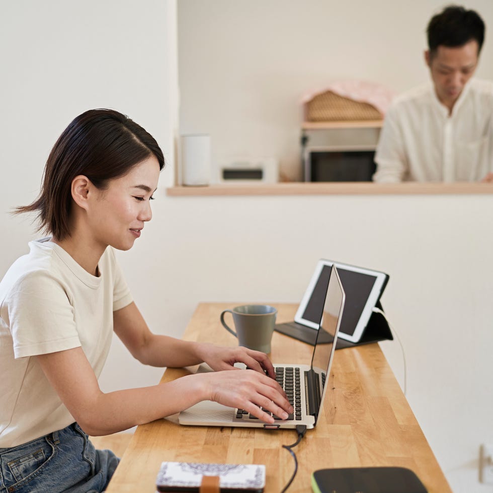 wife working at home office while husband washing dishes in the kitchen