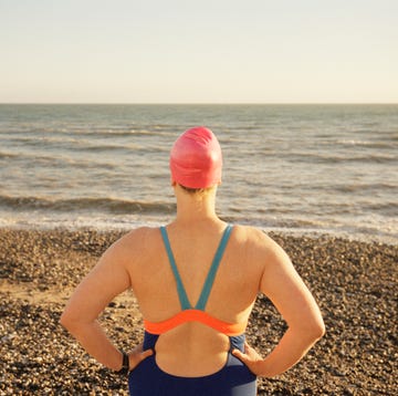 uk, east sussex, eastbourne, beachy head, female swimmer standing on the beach looking out to the sea