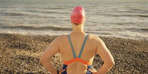 uk, east sussex, eastbourne, beachy head, female swimmer standing on the beach looking out to the sea