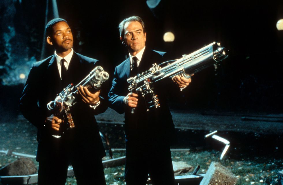 Will Smith and Tommy Lee Jones aiming their weapons towards the sky in a scene from the film 'Men In Black', 1997