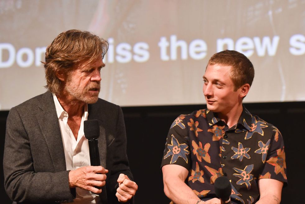 william h macy, wearing a suit jacket and white shirt, talks into a microphone while seated next to jeremy allen white, wearing a floral shit, who also holds a microphone