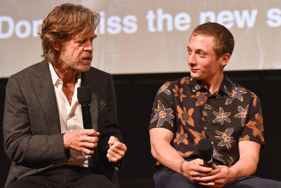 william h macy, wearing a suit jacket and white shirt, talks into a microphone while seated next to jeremy allen white, wearing a floral shit, who also holds a microphone