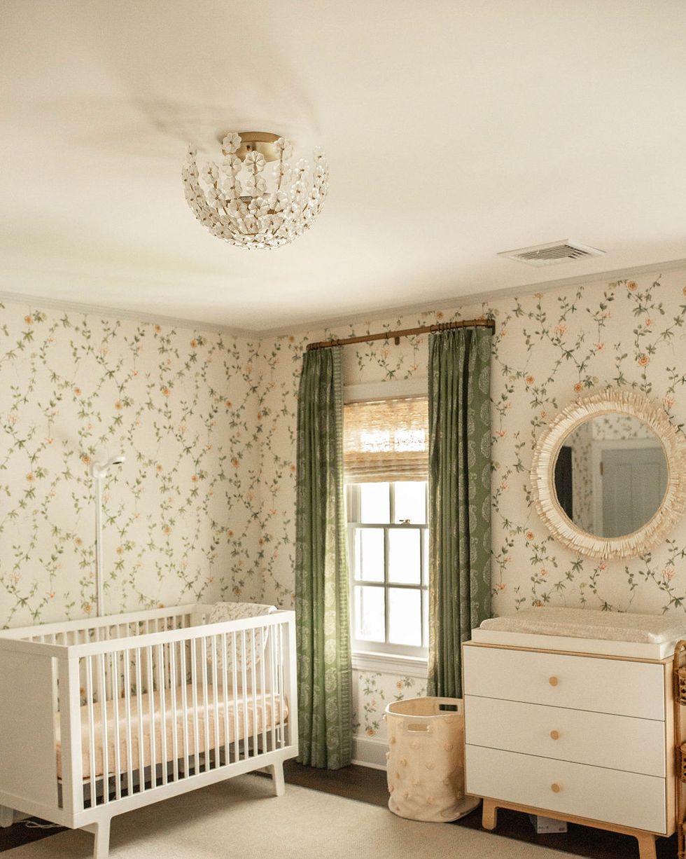 nursery, floral wallpaper, green curtains, white cot, white and wooden dresser, nude area rug