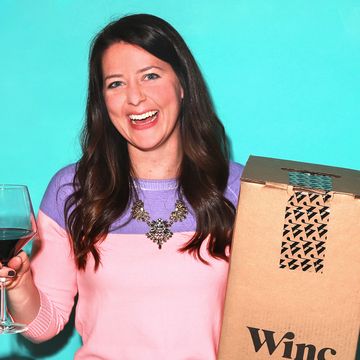 woman holding wine glass with red wine and a winc wine subscription box