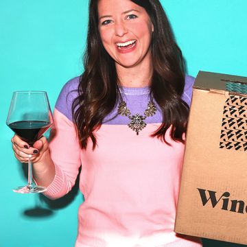 woman holding wine glass with red wine and a winc wine subscription box