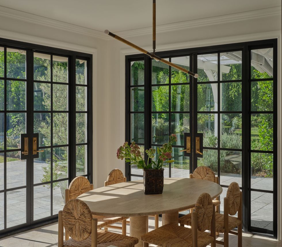 a dining table with chairs and a large window with large glass doors