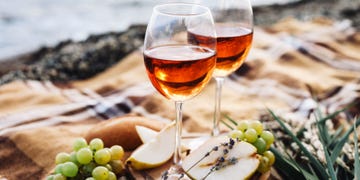 a couple of glasses of wine on a table with a plate of grapes