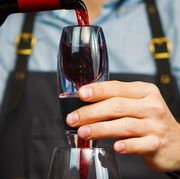man in apron pouring red wine through an aerator