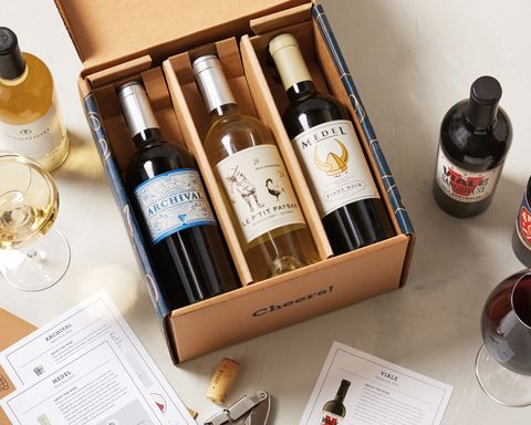 a box of three wine bottles with tasting notes cards and wine bottles around it