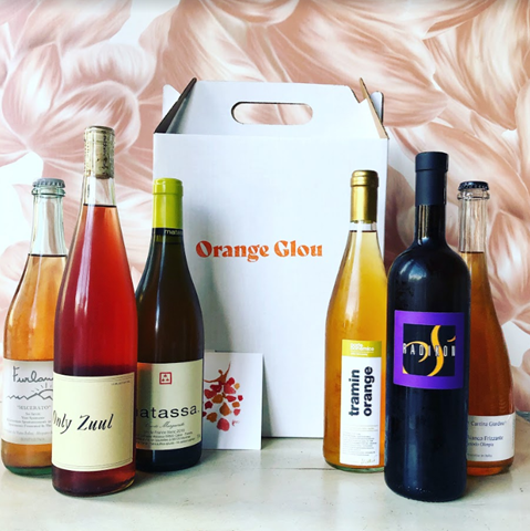 six bottles of wine around a white box that says orange glou